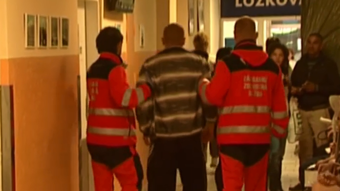 Záchranári odvádzajú opilca na ošetrenie 