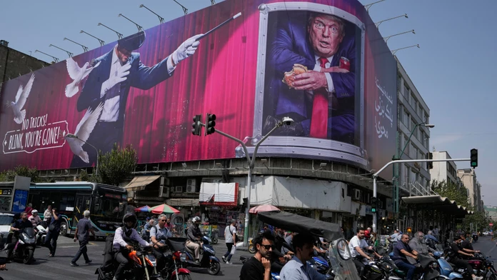 Motocyklisti prechádzajú v centre Teheránu v Iráne okolo billboardu, na ktorom je vyobrazený americký prezident Donald Trump.