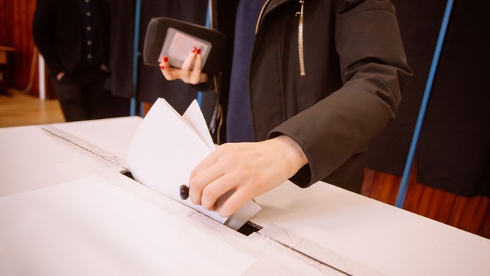 Volič vhadzuje hlasovací lístok do urny.