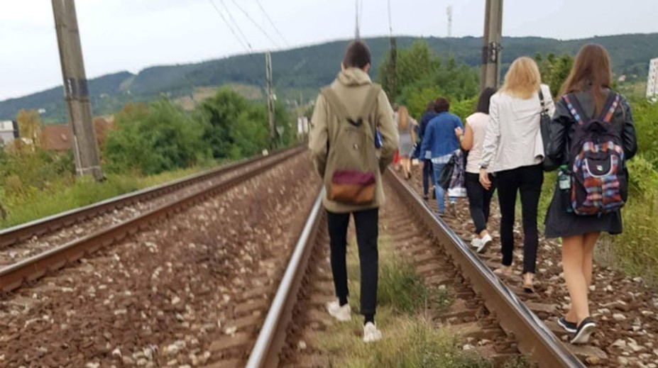 Železniciam sa pokazil vlak. Cestujúci z neho vystúpili a po koľajniciach kráčali na stanicu