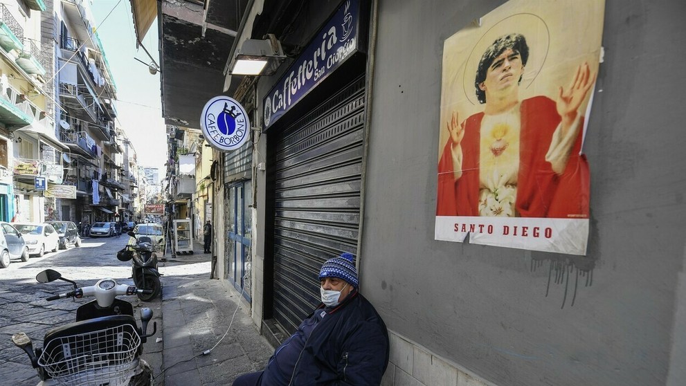 Dôchodca s rúškom sedí pred domom na ulici v Neapole.