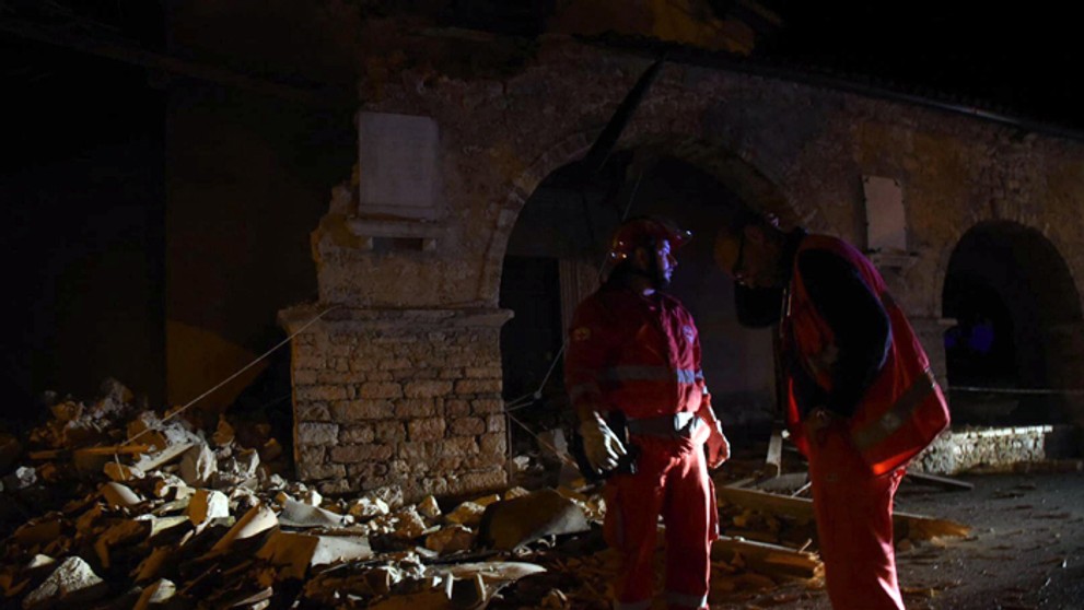 Záchranári si prezerajú sutinu po zemetrasení v talianskej dedine Visso.