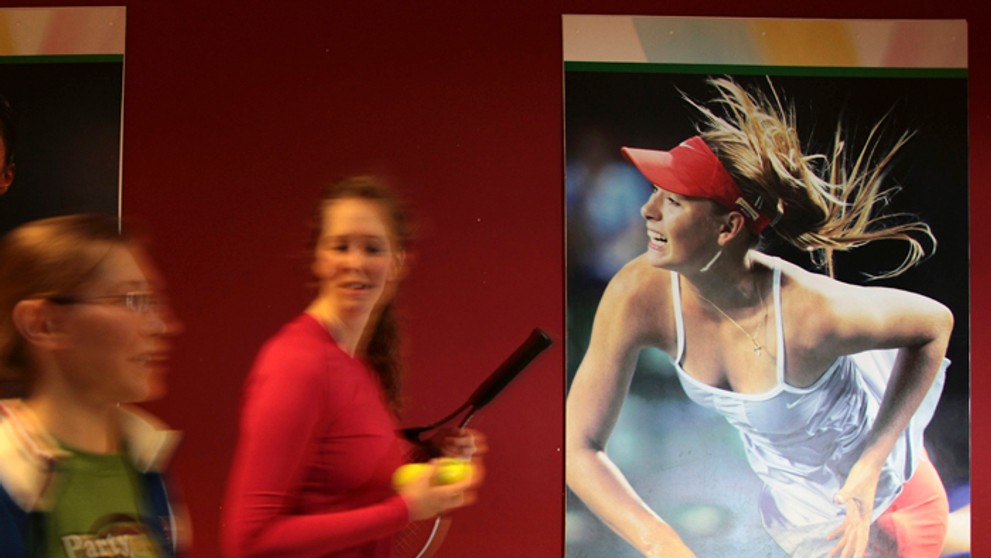 Študentky tenisovej akadémie kráčajú okolo plagátu s podobizňou ruskej tenistky Marie Šarapovovej v Kazani.