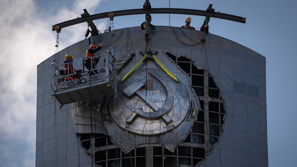 Robotníci odstraňujú štátny znak bývalého Sovietskeho zväzu z obrovskej sochy Matka Vlasť v Kyjeve.