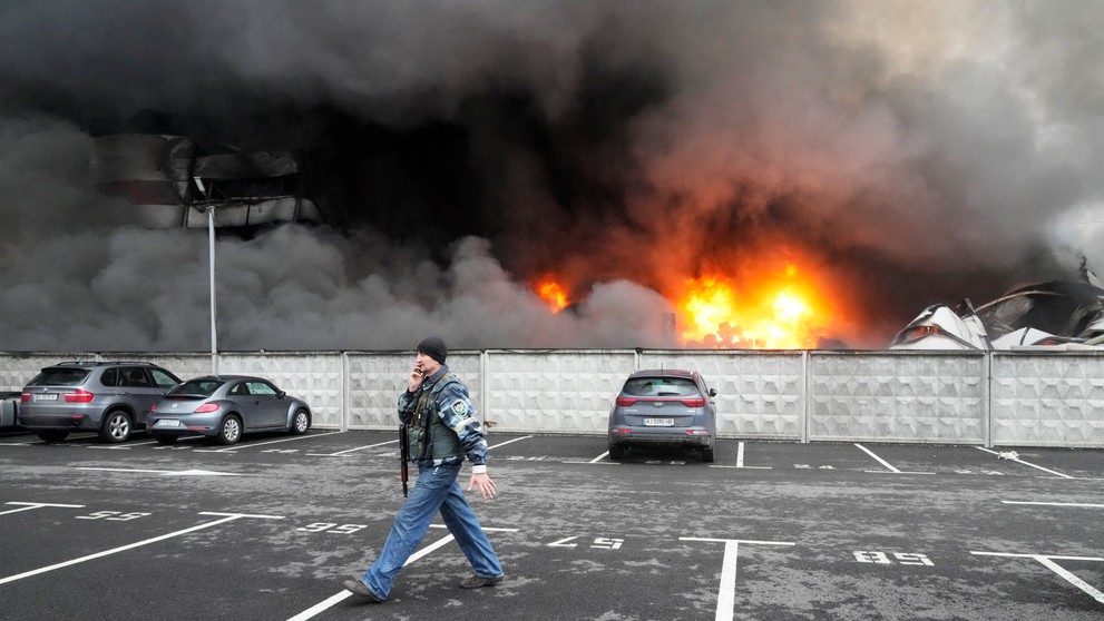 Ukrajinský vojak prechádza okolo poškodeného logistického centra po ostreľovaní v Kyjeve.