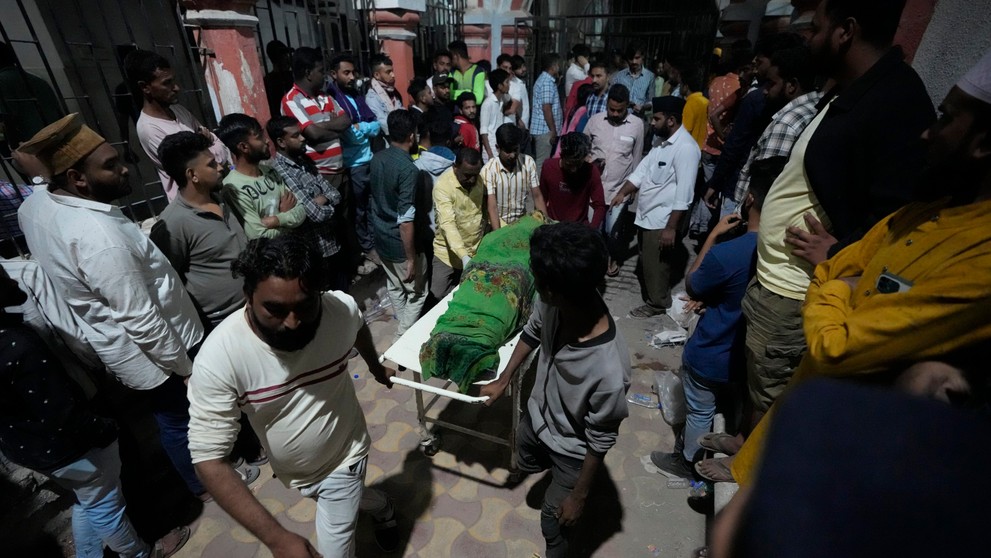 Dobrovoľníci a záchranári odnášajú obete zrúteného mosta v Indii.