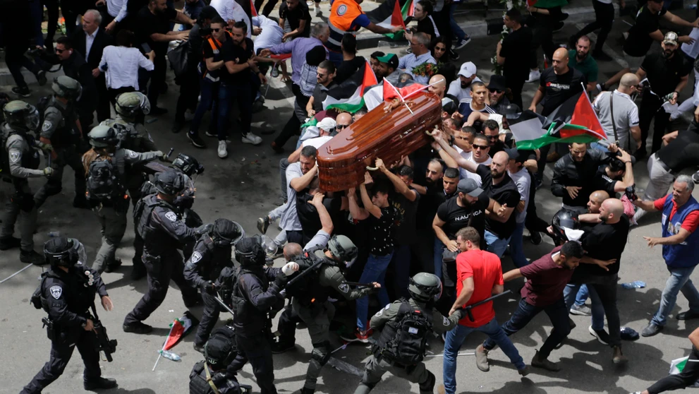 Izraelskí vojaci a policajti zasahujú proti nahnevanému davu na pohrebe novinára televízie Al Jazeera.