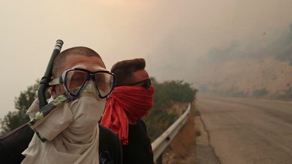 Ľudia si zakrývajú tváre pre stúpajúci dym.