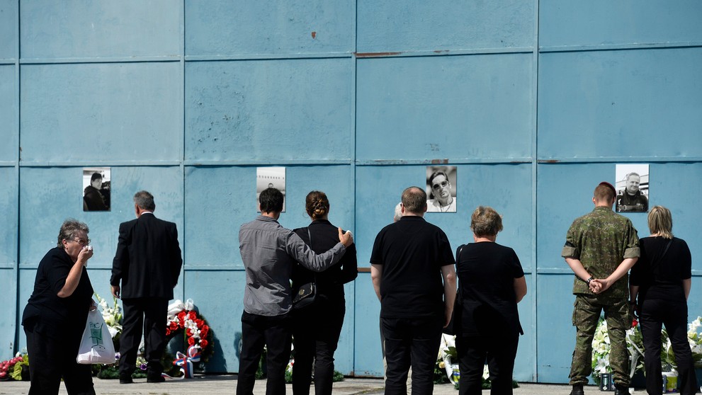 Pozostalí prinášajú kvety k fotografiám obetí leteckého nešťastia na bráne hangára na letisku v Slavnici