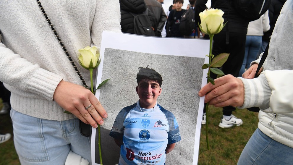 Smútiaci obyvatelia dediny s fotografiou zavraždeného Thomasa.