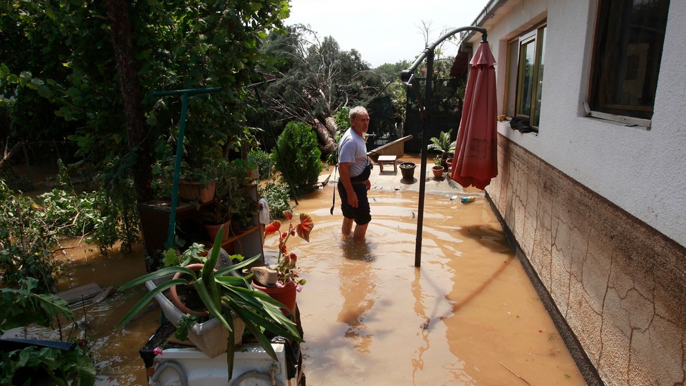 Muž stojí pred zatopeným domom v macedónskej dedine Singelic.