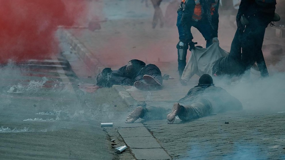 Zranení demonštranti ležia na hodníku po zásahu polície.