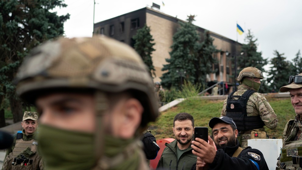 Ukrajinský prezident Volodymyr Zelenskyj pózuje pre selfie s policajtom po vztýčení ukrajinskej vlajky v ukrajinskom meste Izium 14. septembra 2022.
