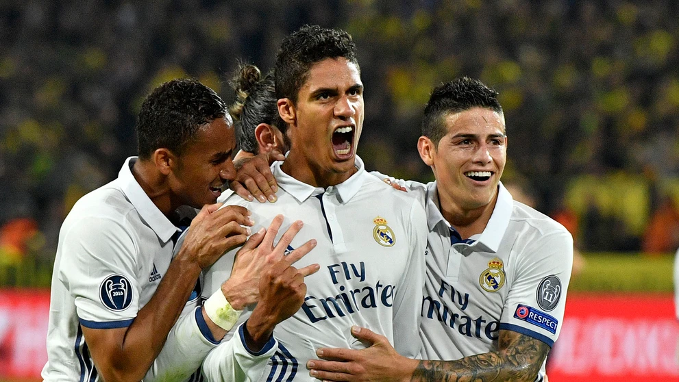 Stopér Realu Madrid Raphael Varane (v strede) oslavuje gól do siete Dortmundu so spoluhráčmi Danilom (vľavo) a Jamesom Rodríguez