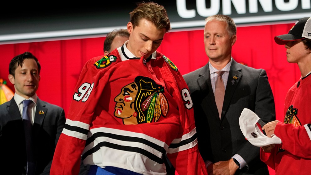 Connor Bedard si oblieka dres Chicaga na NHL drafte 2023.