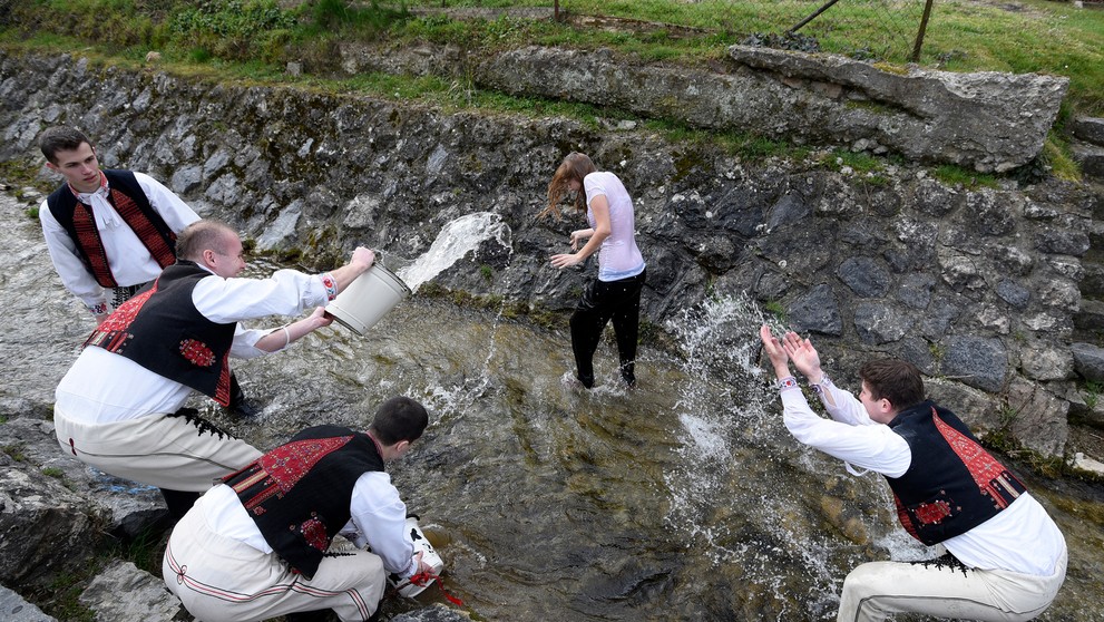 Mládenci v ľudových krojoch z obce Selec neďaleko Trenčína oblievajú dievča v potoku na Veľkončný pondelok.