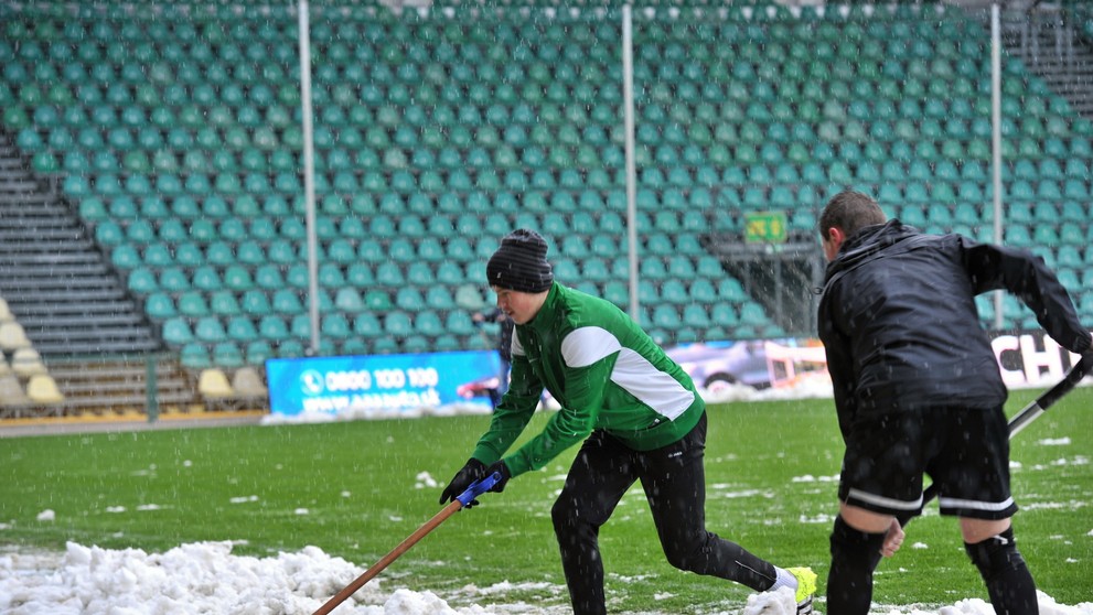 Zamestnanci odpratávajú sneh z hracej plochy na štadióne v Žiline pred zápasom s Trenčínom.