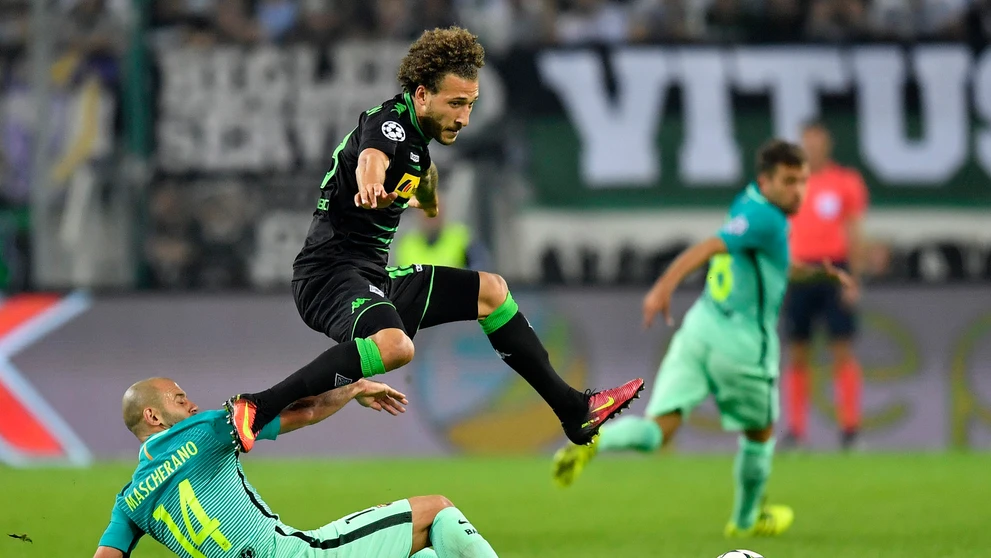 Vo výskoku hráč Borussie Mönchengladbach Fabian Johnson, na zemi v ostrom sklze defenzívna opora Barcelony Javier Mascherano v d
