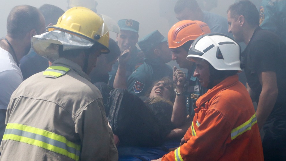 Hasiči vynášajú zranenú ženu 