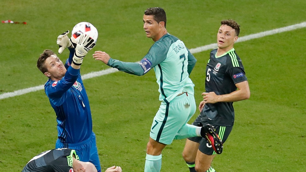 Waleský gólman Wayne Hennessey chytá loptu pred obávaným Cristianom Ronaldom z Portugalska v semifinále ME.