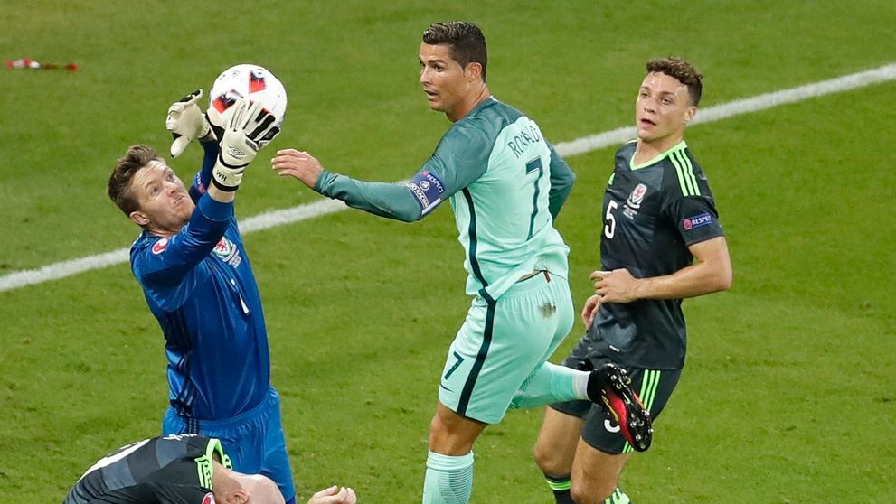 Waleský gólman Wayne Hennessey chytá loptu pred obávaným Cristianom Ronaldom z Portugalska v semifinále ME.