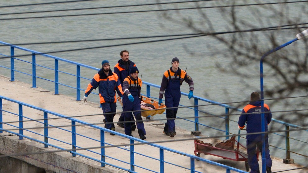 Ruskí záchranári nesú telo z vraku zrúteného lietadla typu Tu-154 na móle neďaleko Soči.