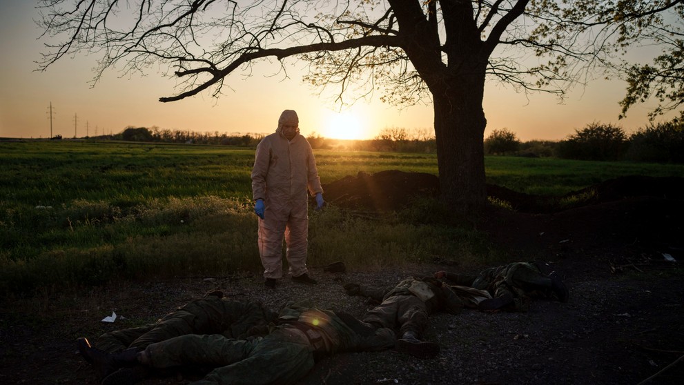  Ukrajinský pracovník pre mimoriadne situácie stojí pri telách 11 ruských vojakov, ktorí ležia na zemi v dedine Vilchivka, neďaleko Charkova, ktorú nedávno prevzali pod kontrolu ukrajinské jednotky.