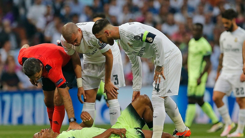 Arbiter Damir Skomina (v červenom), hráči Realu Pepe a Sergio Ramos (s kapitánskou páskou) hľadia na zraneného Vincenta Kompanyh