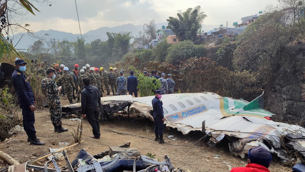 Záchranári stoja pri troskách osobného lietadla, ktoré sa zrútilo v obci Pokhará v Nepále.