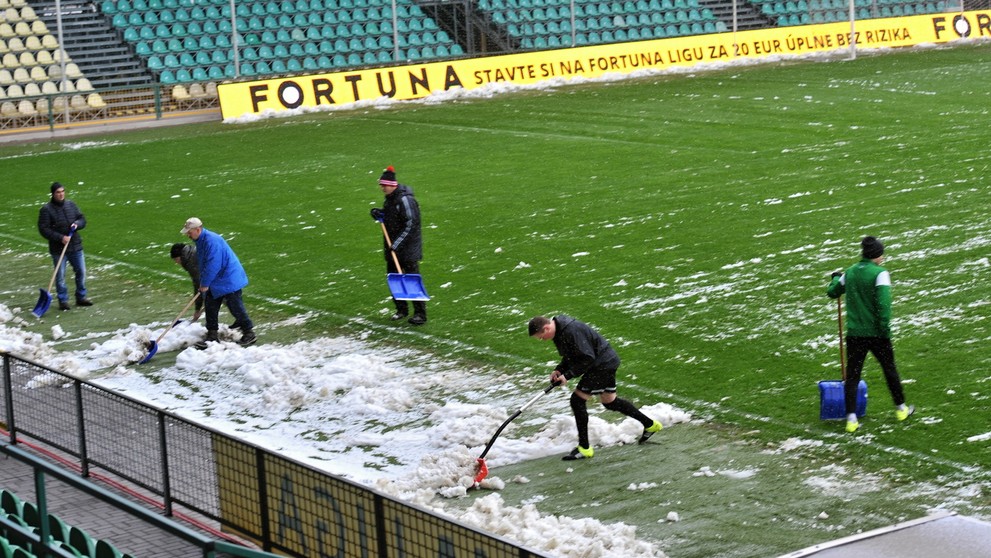 Zamestnanci odpratávajú sneh z hracej plochy na štadióne v Žiline pred zápasom s Trenčínom.