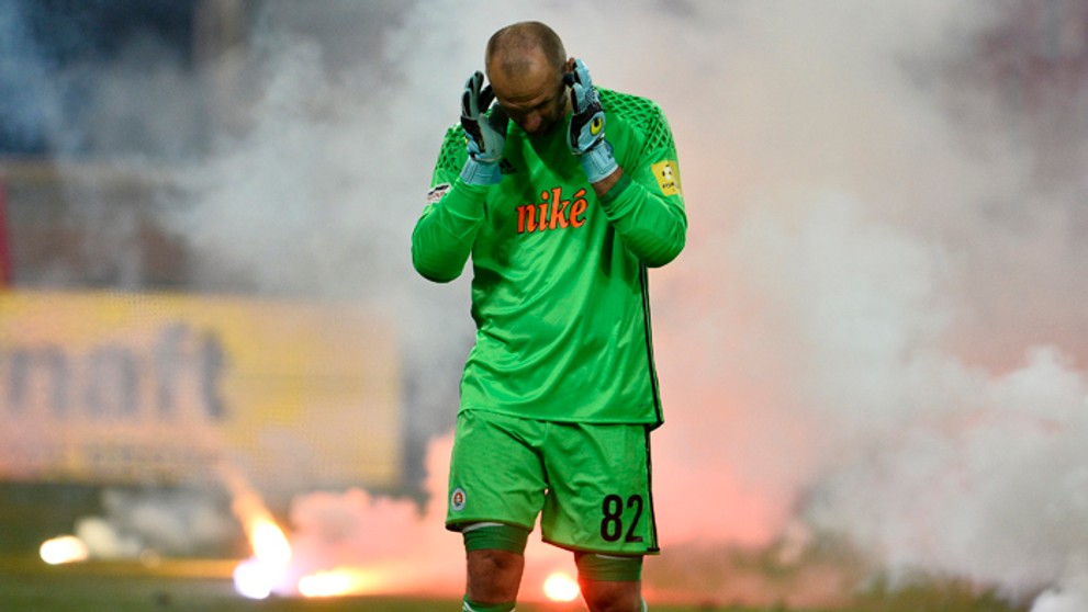 Brankár Slovana Ján Mucha si zapcháva uši po tom, čo priestor pred jeho bránkou zahádzali fanúšikovia Slovana pyrotechnikou.