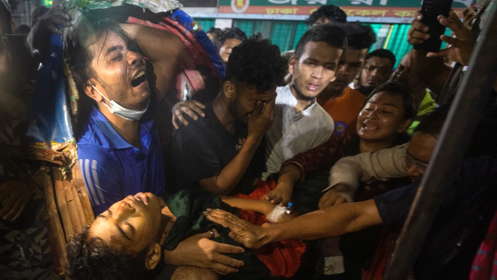 Na snímke muži plačú nad mŕtvym telom muža, ktorý bol zabitý na protivládnych protestoch v Bangladéši.