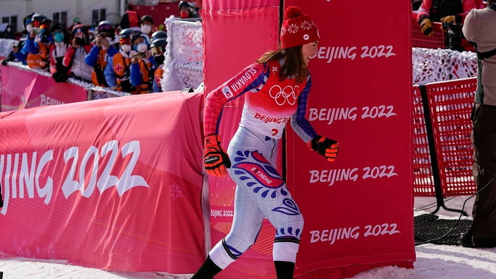 Lyžiarka Petra Vlhová uteká za svojim tímom oslavovať zlato v slalome na ZOH 2022.