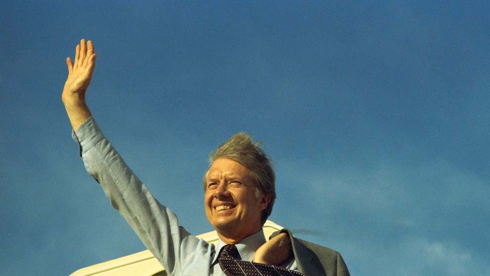 Americký prezident Jimmy Carter mával na schodoch Air Force One pred odletom do Los Angeles, aby vystúpil na zjazde United Auto Workers 17. mája 1977.