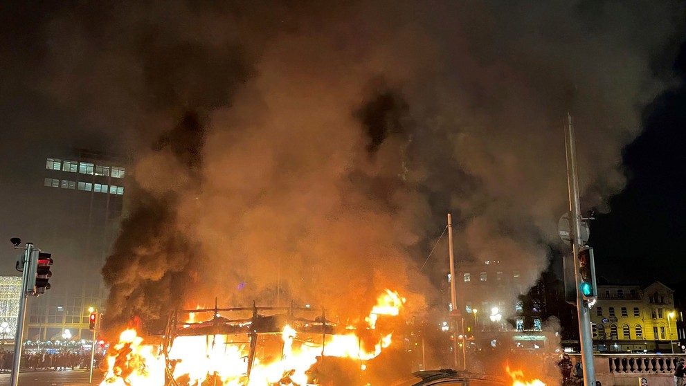 Na snímke auto a autobus horia  počas demonštrácie po útoku v centre Dublinu