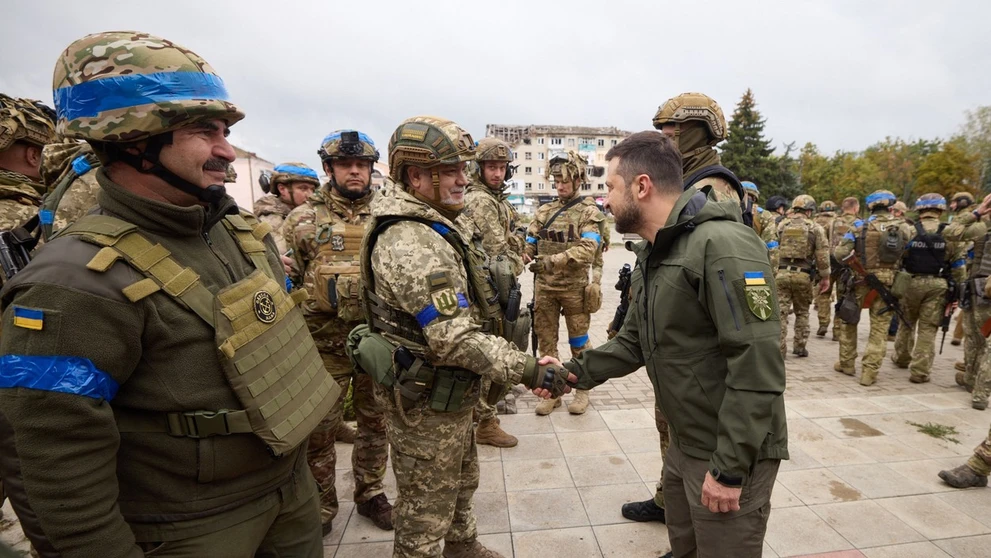 Prezident Zelenskyj si podáva ruku s ukrajinským vojakom v meste Izium.