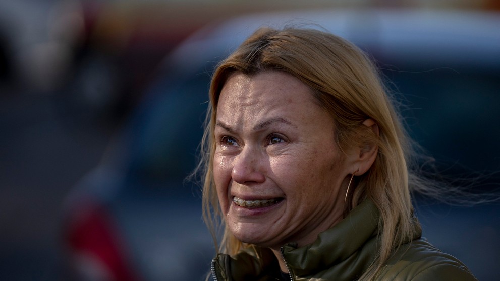 Žena plače, keď sa pozerá na zničený bytový dom po raketovom útoku