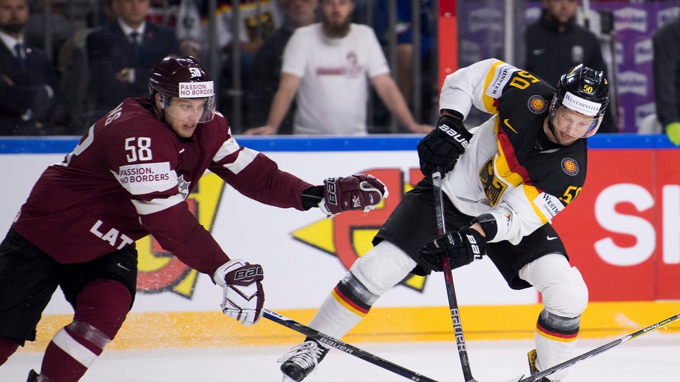 Patrick Hager (vpravo) z Nemecka drží puk pred Lotyšom Guntisom Galvinšom v zápase MS 2017.