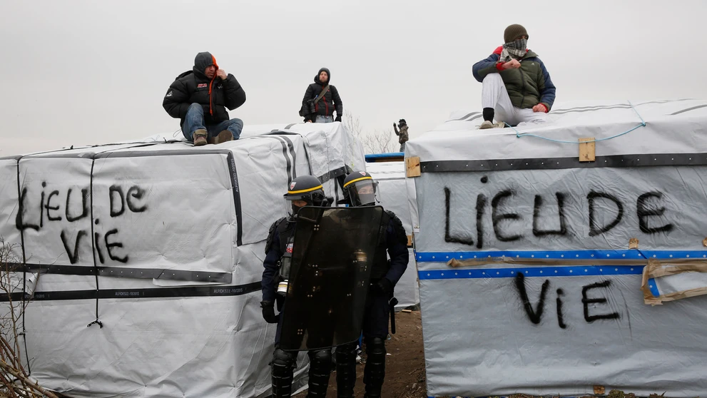 Migranti v tábore pri Calais protestujú na strechách búd.