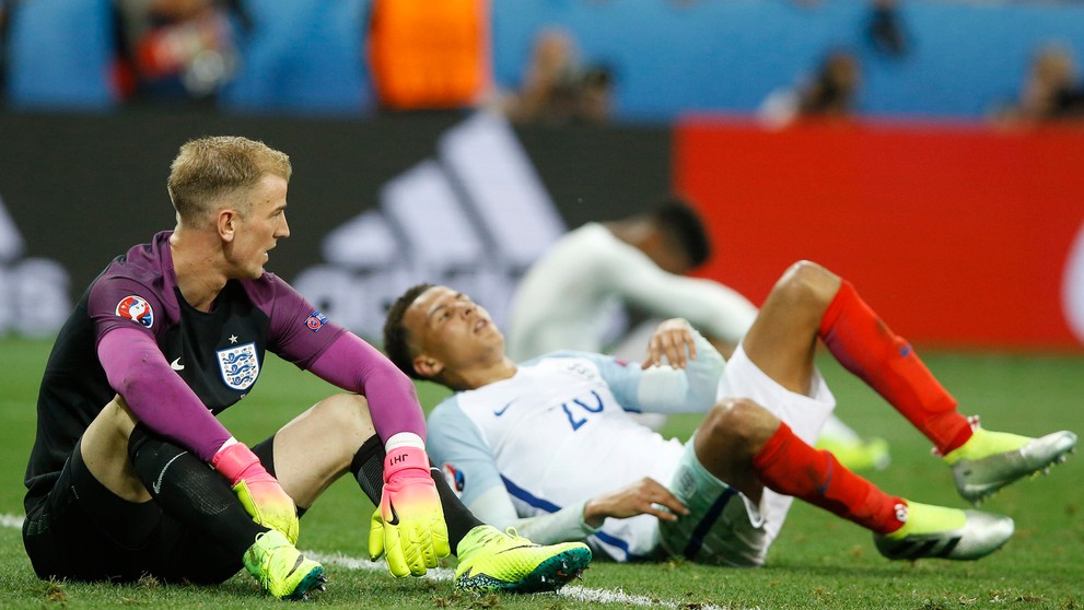 Anglickí futbalisti brankár Joe Hart (vľavo) a Dele Alli sedia na trávniku po osemfinálovom vypadnutí na ME s Islandom.
