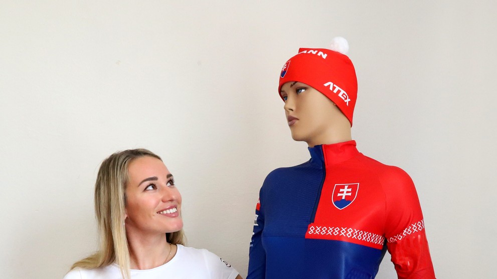 Paulína Bátovská Fialková stojí pri novej reprezentačnej kombinéze počas tlačovej konferencie Slovenského zväzu biatlonu.