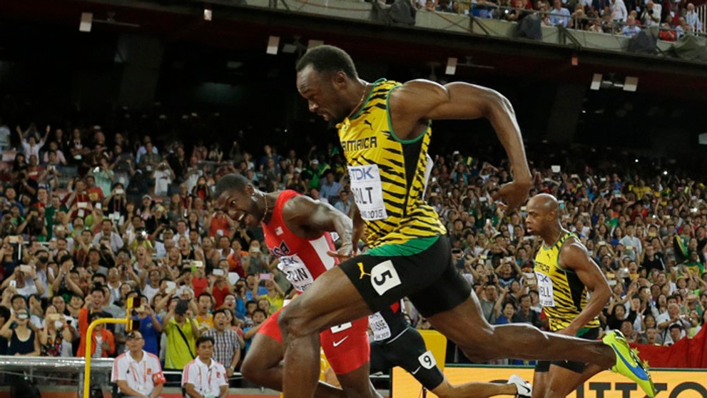 Usain Bolt víťazi vo finále na 100 m na MS v atletike o sekundu pred Justinom Gatlinom (USA) v červenom drese.