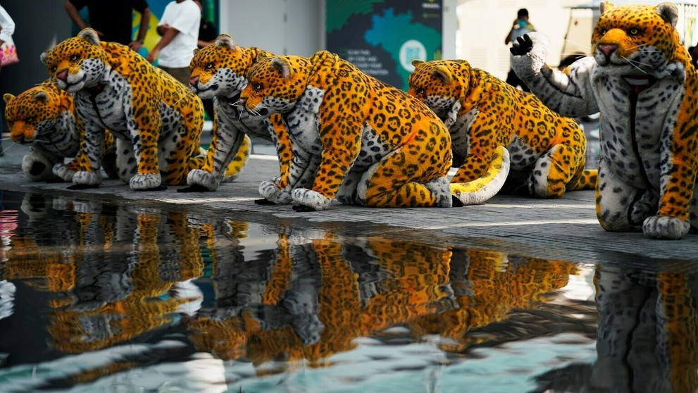 Skupina vystupujúcich prezlečená za jaguárov pózuje pri vode v pavilóne  Brazílie.