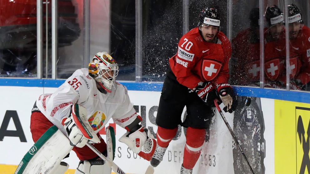 Gólman Bieloruska Kevin Lalande (vľavo) sa snaží chytiť puk pred Denisom Hollensteinom v dueli MS 2017.