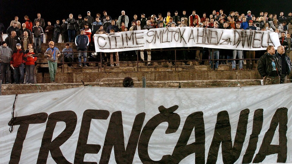 Horiace sviečky, transparent s nápisom "Cítime smútok a hnev za Daniela"