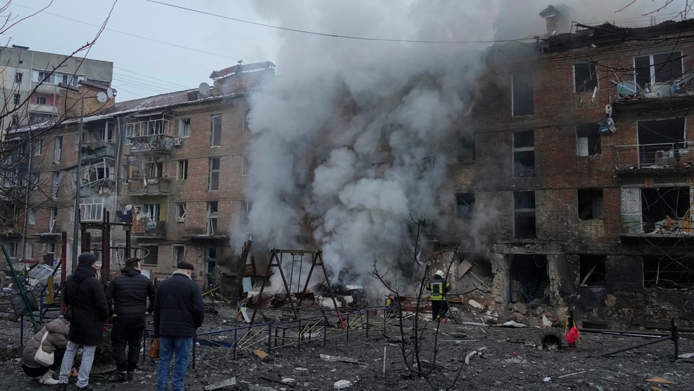 Ľudia si prezerajú materiálne škody na obytnej budove po ruskom raketovom útoku v Kyjeve.