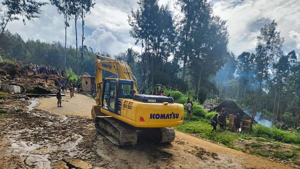 Dedinčania ťažkým mechanizmom prehľadávajú oblasť postihnutú zosuvom pôdy v dedine Yambali.