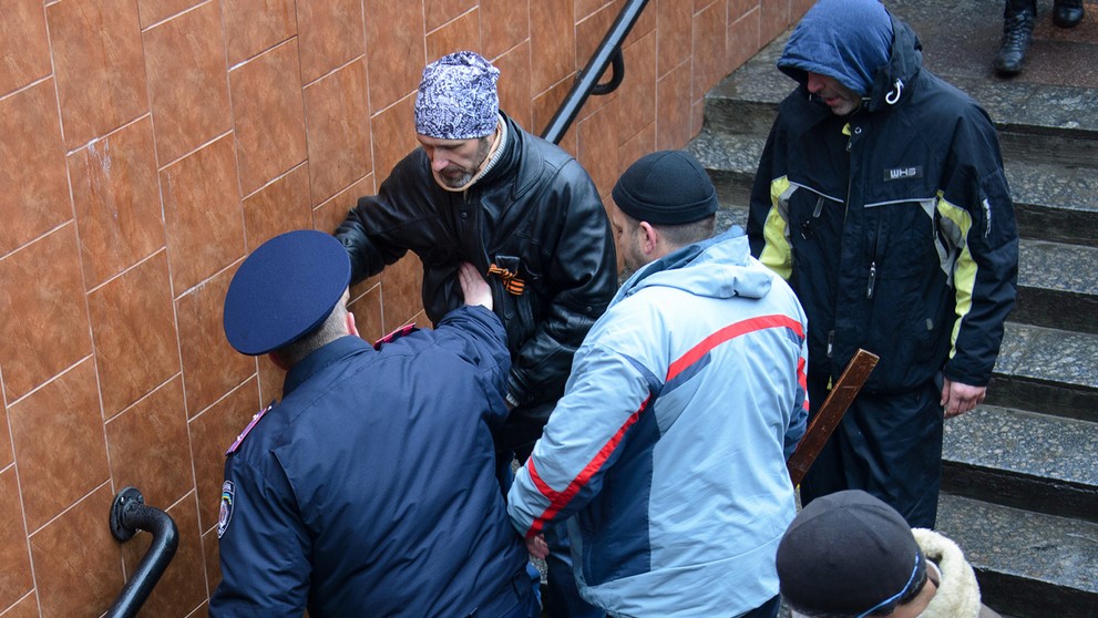 Ukrajinský policajt zastavuje proruského aktivistu, ktorý chcel biť ukrajinského demonštranta (dole na schodoch) v ukrajinskom C