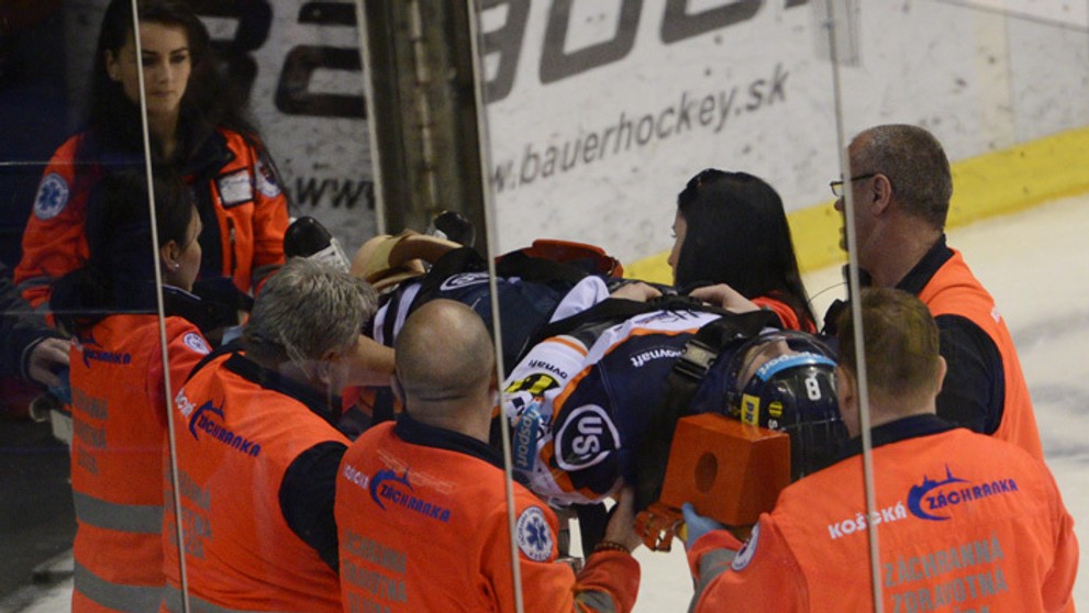 Záchranári odnášajú na nosidlách z ľadovej plochy zraneného hokejistu Košíc Branislava Pavúka.