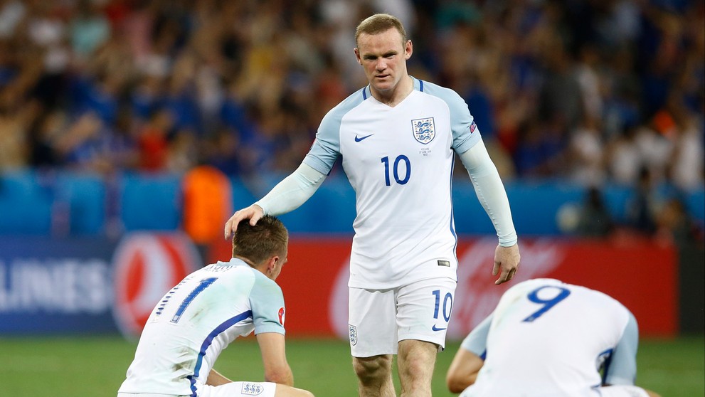 Anglický futbalista Wayne Rooney utešuje svojich spoluhráčov po osemfinálovej prehre s Islandom na ME.